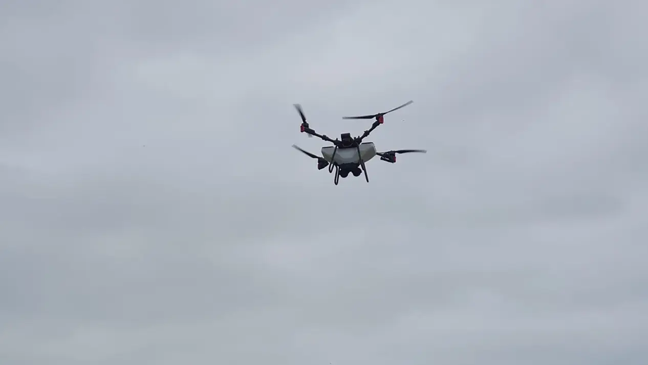 Drone applying foliar feed to crops under rainy sky