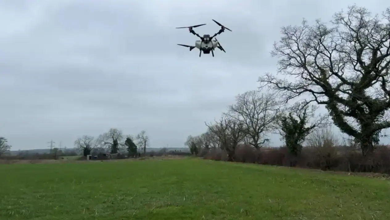 Agricultural drone spreading seed over an arable field during a cover crop operation